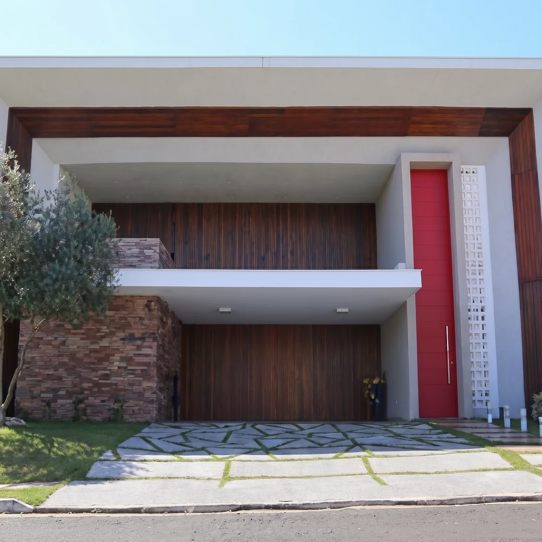 Residência de fachada horizontal, com revestimento de madeira, pedra e porta vermelha.